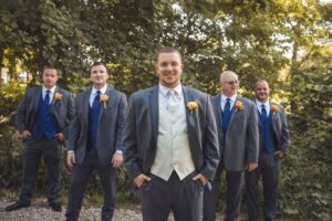 Stylish groom and groomsmen wearing dark grey, blue and a touch of pink