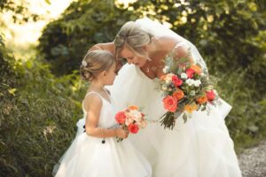 Bride and flower girl hugging at an elegant garden wedding venue near Ann Arbor Michigan