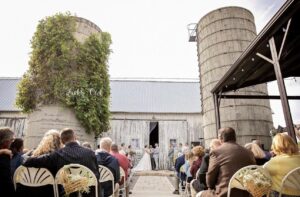 Wedding guests are watching the bride and groom exchange vows at their barn wedding venue near Ann Arbor