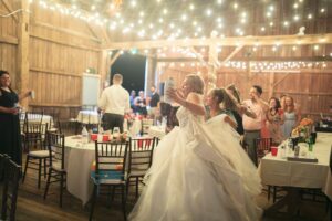 Bride wearing a designer wedding dress as she dances at the reception with wedding guests, near Ann Arbor