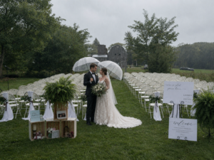 Bride and groom holding umbrellas as they kiss in the rain at their outdoor wedding ceremony near Ann Arbor
